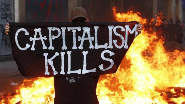An anti-G20 protester stands in front of a burning street barricade and poses with a flag reading ‘Captitalism Kills’ in Germany. (REUTERS) An anti-G20 protester stands in front of a burning street barricade and poses with a flag reading ‘Captitalism Kills’ in Germany. (REUTERS)