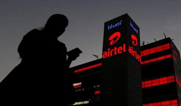 A girl checks her mobile phone as she walks past the Bharti Airtel office building in Gurgaon.(REUTERS)