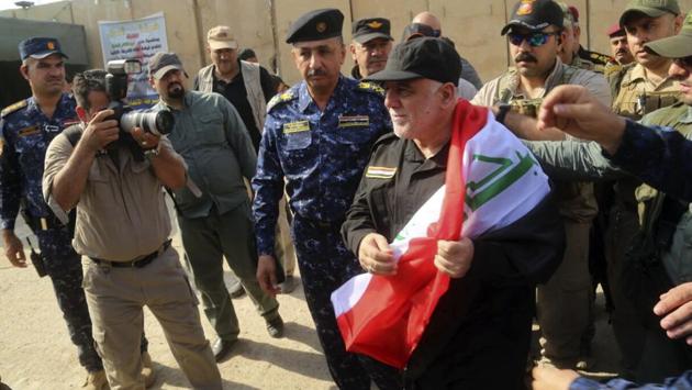 Iraq's Prime Minister Haider al-Abadi, center, holds a national flag upon his arrival to Mosul, Iraq, Sunday, July 9, 2017. Backed by the U.S.-led coalition, Iraq launched the operation to retake Mosul from Islamic State militants in October. (AP) Iraq's Prime Minister Haider al-Abadi, center, holds a national flag upon his arrival to Mosul, Iraq, Sunday, July 9, 2017. Backed by the U.S.-led coalition, Iraq launched the operation to retake Mosul from Islamic State militants in October. (AP)