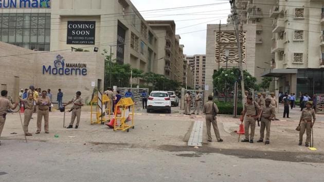 Policemen stand guard outside a housing society, Mahagun Moderne in Noida Sector 78 on Wednesday after a mob attacked the society.(Sohil Sehran/HT Photo)