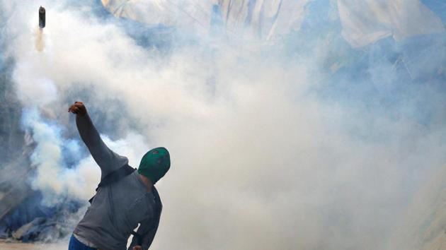 A stone pelter lobs a tear gas canister back at police during disturbances in Srinagar, India. Many young men in the state’s summer capital of Srinagar, find themselves fighting street battles, slinging stones at pellet gun wielding police officers from their own communities, and even their own families engaged in opposing sides of the turmoil. (Cathal McNaughton / REUTERS)