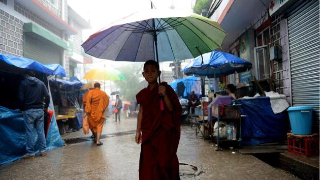 A young Tibetan Buddhist monk cross a street during rain in Mcleodganj near Dharamsala on Wednesday. (Shyam Sharma/HT Photo)