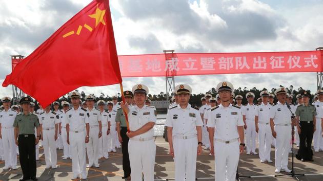 A soldier of China's People's Liberation Army holds a PLA flag as others stand guard at a military port in Zhanjiang, Guangdong province on Tuesday. (REUTERS) A soldier of China's People's Liberation Army holds a PLA flag as others stand guard at a military port in Zhanjiang, Guangdong province on Tuesday. (REUTERS)
