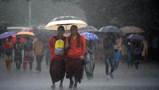 Monks strolling with umbrella during heavy rainfall at the Ridge, Shimla, on Wednesday. (Deepak Sansta/HT Photo)