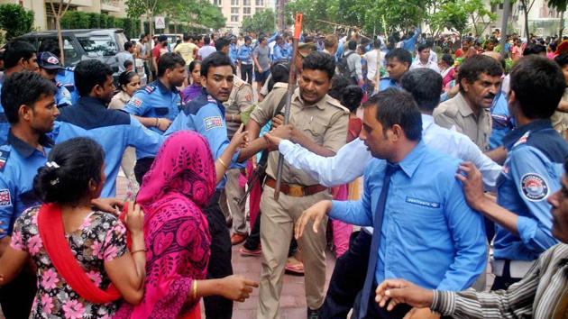 Noida: Police and private security personnel in a clash with the local villagers who gathered at a housing society to protest after a domestic help was allegedly beaten by her employers on suspicion of theft, in Noida on Wednesday. (PTI) Noida: Police and private security personnel in a clash with the local villagers who gathered at a housing society to protest after a domestic help was allegedly beaten by her employers on suspicion of theft, in Noida on Wednesday. (PTI)