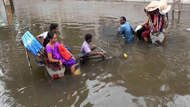 Rickshaw pullers wades through a flooded street after heavy downpour in Patna. (PTI) 