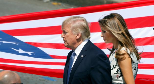 US President Donald Trump and First Lady Melania Trump stand in front of the American flag at the end of the traditional Bastille Day military parade on the Champs-Elysees in Paris on July 14, 2017.(REUTERS)