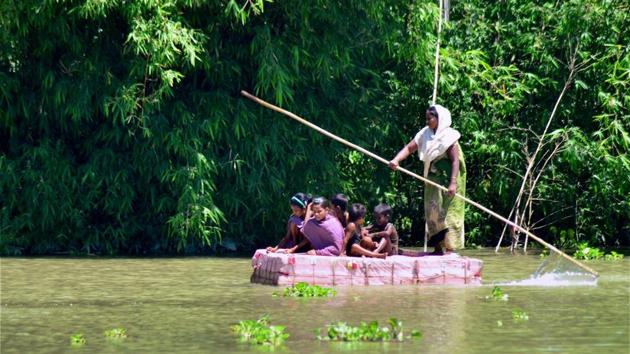 A woman with her children rows a makeshift raft across flood waters in the Kamrup district of Assam.(PTI Photo)