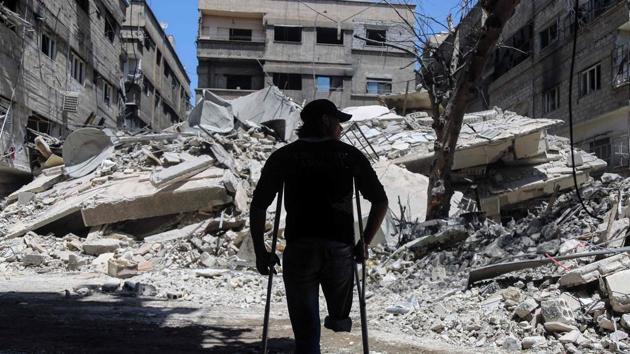 A Syrian amputee uses crutches to walk next to a building that was destroyed following a reported air strike on the rebel-held town of Ayn Tarma, in Syria's eastern Ghouta area (AMER ALMOHIBANY/AFP) A Syrian amputee uses crutches to walk next to a building that was destroyed following a reported air strike on the rebel-held town of Ayn Tarma, in Syria's eastern Ghouta area (AMER ALMOHIBANY/AFP)