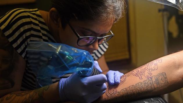 A tattoo artist attends to a customer at her workshop at Dadar. (Satyabrata Tripathy/HT Photo)