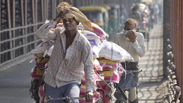 A man wipes sweat form his forehead as he ferries goods in hot weather on his cycle rickshaw across the Old Yamuna bridge in New Delhi.(Gurinder Osan/HT file photo)