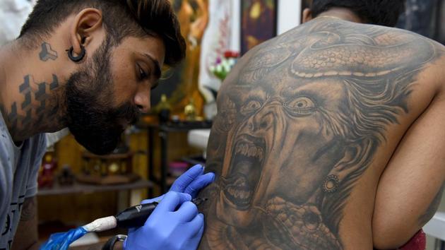 A tattoo artist bust at work at his workshop in Kopar Khairane in Navi Mumbai. (Bachchan Kumar /HT PHOTO)