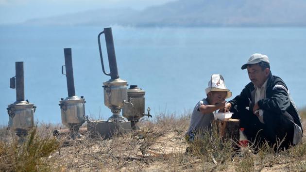 A Kyrgyz man and his son share from a bowl of food next to samovars during the 'Ethno Fest' festival in the village of Ton, near Issyk-Kul lake, some 350km from the Kyrgyz capital of Bishkek. (Vyacheslav Oseledko / AFP) A Kyrgyz man and his son share from a bowl of food next to samovars during the 'Ethno Fest' festival in the village of Ton, near Issyk-Kul lake, some 350km from the Kyrgyz capital of Bishkek. (Vyacheslav Oseledko / AFP)
