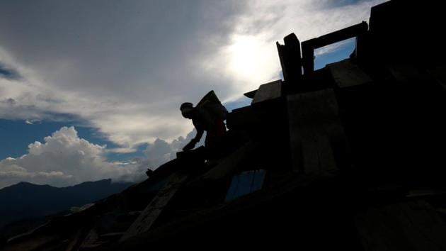A woman is silhouetted as she carries bricks from the debris of a monastery damaged during the 2015 earthquake, in Swayambhunath Stupa, in Kathmandu, Nepal.(REUTERS/Representative image)