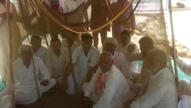 Villagers huddle under a net as they hold a sit-in protesting the menace of mosquitoes. (HT Photo) Villagers huddle under a net as they hold a sit-in protesting the menace of mosquitoes. (HT Photo)
