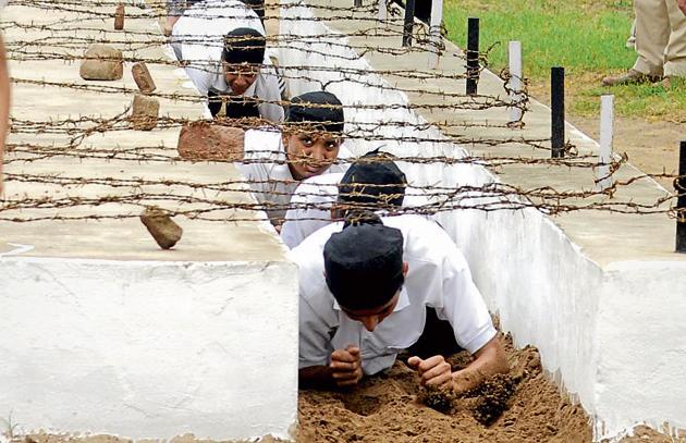 Cadets crawling under barbed wires during teh training session. (Bharat Bhushan/HT)