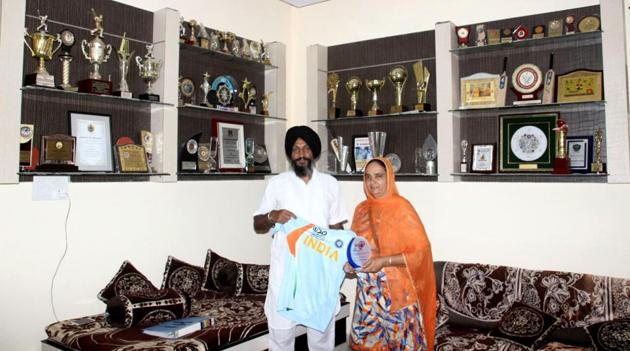 Harmanpreet's father Harmandar Singh and mother Satvinder Kaur showing a T-shirt and awards won by her. (HT Photo )