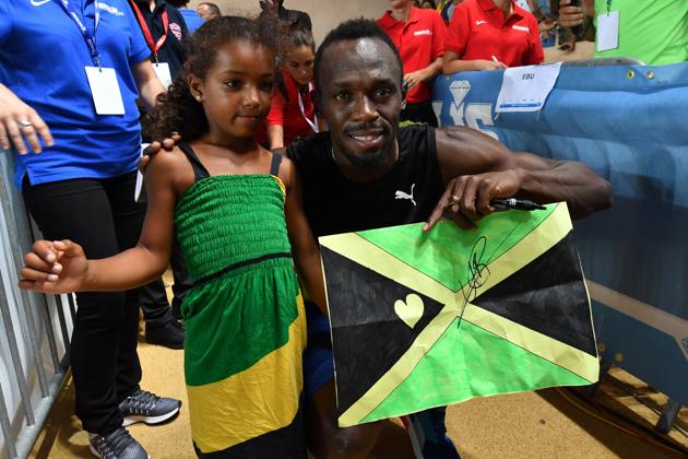 Usain Bolt even took out time to pose with a girl who gave him a drawing of the Jamaican flag. (AFP) Usain Bolt even took out time to pose with a girl who gave him a drawing of the Jamaican flag. (AFP)