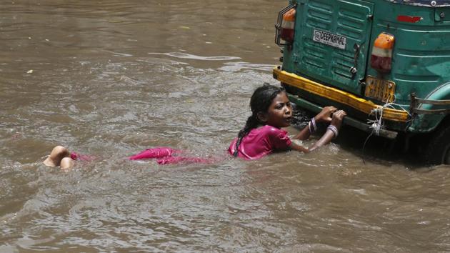 A girl holds on to the back of an auto-rickshaw as she plays in a flooded street with other children after a heavy monsoon rain in Ahmadabad, Gujarat. (Ajit Solanki / AP) A girl holds on to the back of an auto-rickshaw as she plays in a flooded street with other children after a heavy monsoon rain in Ahmadabad, Gujarat. (Ajit Solanki / AP)