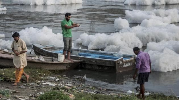 A man offers prayers as a priest walks past at a ghat of the polluted Yamuna river. (PTI) A man offers prayers as a priest walks past at a ghat of the polluted Yamuna river. (PTI)