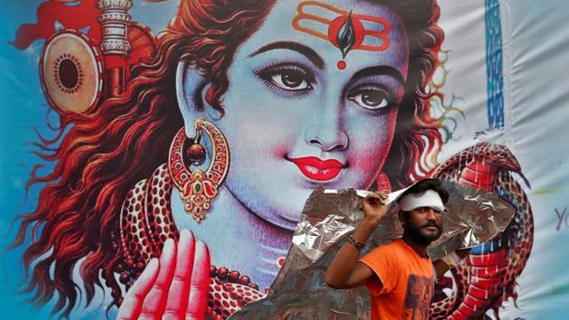 A Kanwaria or devotee of Hindu god Shiva shelters from the rain in front of a poster of Lord Shiva in New Delhi, India. (Cathal McNaughton / REUTERS) A Kanwaria or devotee of Hindu god Shiva shelters from the rain in front of a poster of Lord Shiva in New Delhi, India. (Cathal McNaughton / REUTERS)