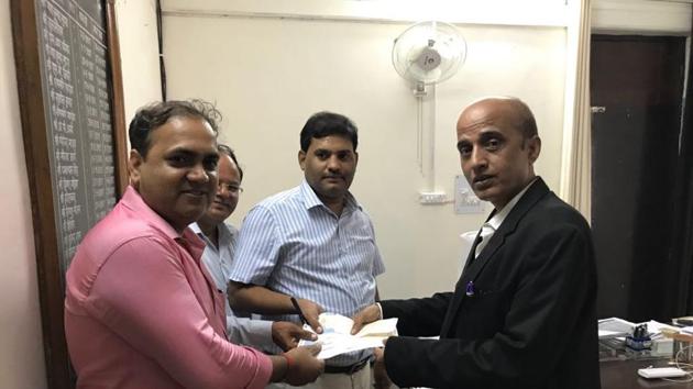 The lawyer for the Amrapali group hands over the DD of the pending amount to Dadri tehsildar PL Maurya (right), on Tuesday.