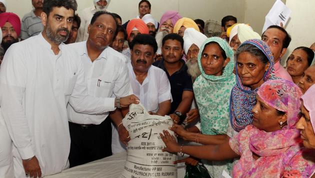 Jaijeet Singh Johal, brother-in-law of Punjab finance minister Manpreet Singh Badal,handing over wheat bags to atta-dal scheme beneficiaries in Bathinda on Monday.(Sanjeev Kumar/HT)