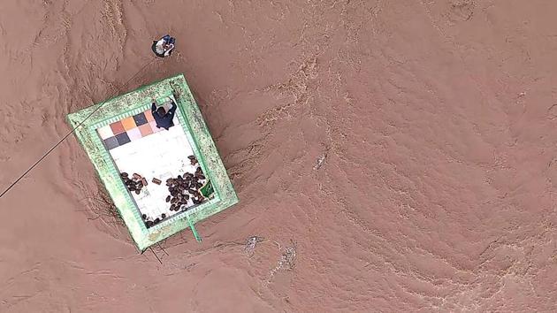 An Indian Air Force (IAF) officer after being lowered from a helicopter to help local residents taking shelter atop a Dargah (Muslim Shrine) surrounded by flood waters at Untadi village of Limdi Taluka, some 100 kms from Ahmedabad. (AFP) An Indian Air Force (IAF) officer after being lowered from a helicopter to help local residents taking shelter atop a Dargah (Muslim Shrine) surrounded by flood waters at Untadi village of Limdi Taluka, some 100 kms from Ahmedabad. (AFP)