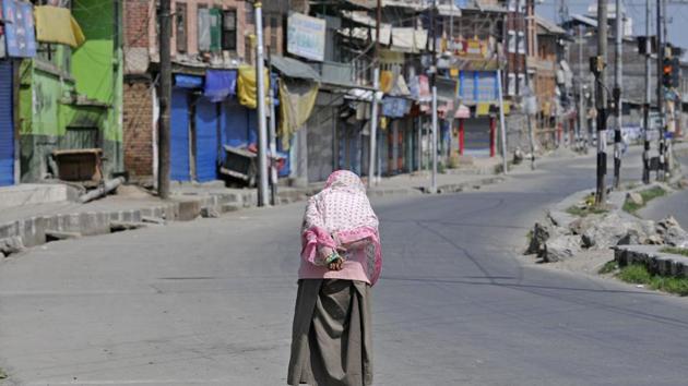 A woman walks on a deserted street in downtown Srinagar on Tuesday. Normal life was hit in the old parts of the city following Hurriyat’s shutdown call and authorities restricting movement of the people.(Waseem Andrabi / HT photo)
