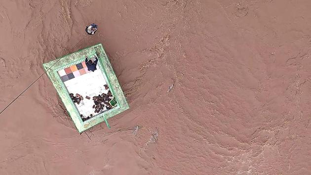 This official handout photograph shows an Indian Air Force (IAF) personnel after being lowered from an helicopter to help residents taking shelter atop a dargah surrounded by flood waters in Gujarat. (AFP Photo) This official handout photograph shows an Indian Air Force (IAF) personnel after being lowered from an helicopter to help residents taking shelter atop a dargah surrounded by flood waters in Gujarat. (AFP Photo)