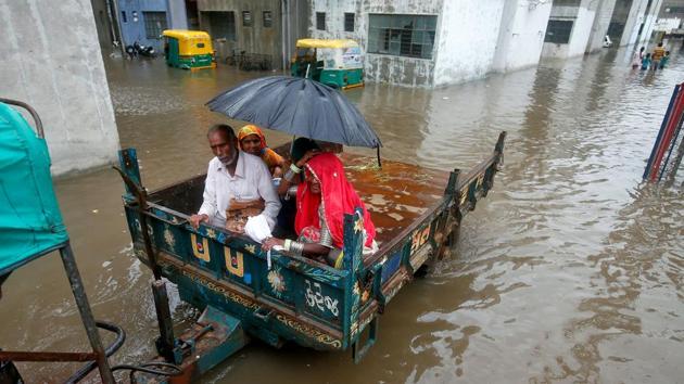 People sit in a tractor trolley as they move out of a flooded neighbourhood after heavy rain in Ahmedabad, India, July 24, 2017.(REUTERS)