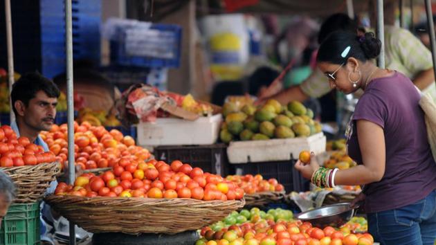 A woman buys tomatoes in a vegetable market. Tomato prices touched Rs 100 per kilogram in some districts of West Bengal.(HT File)