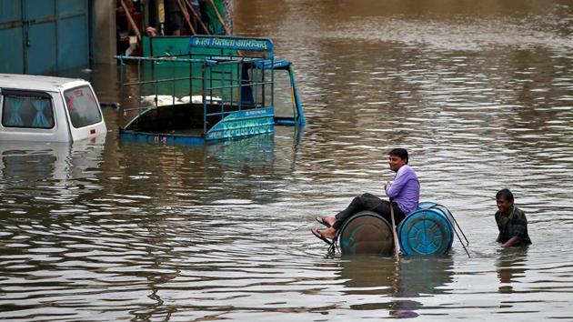 A man uses a makeshift raft to move out of a flooded neighbourhood after heavy rains in Ahmedabad. Approximately 600 people have died in floods and landslides across the country this year. (Amit Dave / REUTERS)