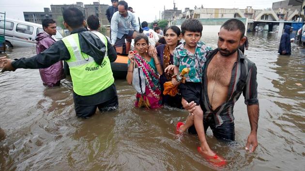 Fire officials and rescuers evacuate people from a flooded neighbourhood after heavy rains in Ahmedabad. (Amit Dave / REUTERS)