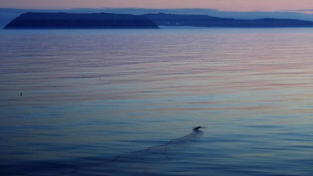 A bird's wake is cast on the water with the American islands of Little Diomede, Alaska (L), and behind it the Russian island of Big Diomede (R), are seen from the Finnish icebreaker MSV Nordica in the Bering Strait. The international date line divides the two islands, putting them currently 20 hours apart despite roughly 3.8 kms separating them. Due to this time difference, Little Diomede is sometimes referred to as Yesterday Isle and Big Diomede as Tomorrow Island. (David Goldman / AP)