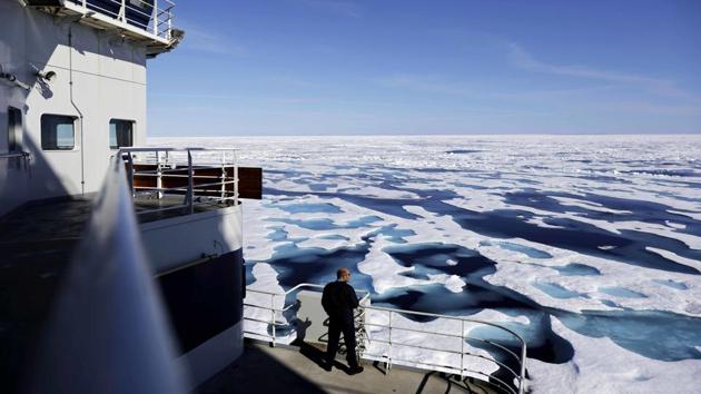 Canadian Coast Guard Capt. Victor Gronmyr looks out over the ice covering the Victoria Strait, visibly pockmarked by signs of melting in the summer months. (David Goldman / AP)