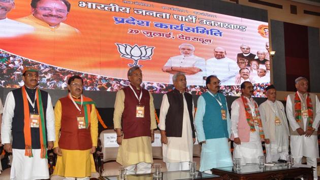 Chief minister Trivendra Singh Rawat and other BJP leaders rise for singing national song at the inaugural session of the BJP's state executive committee meeting in Dehradun on Saturday.(Vinay Santosh Kumar//HT)
