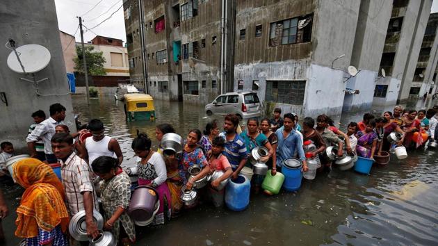 People queue to collect drinking water from a municipal tanker at a flooded residential colony in Ahmedabad. (REUTERS/Amit Dave )