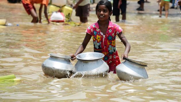 A girl with containers wades through flood waters to collect drinking water in Amta area of Howrah district in West Bengal.(AFP)