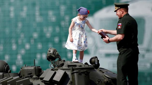 A Russian serviceman stands with a girl on top of a T-72 tank on display during the opening ceremony of the International Army Games 2017 in Alabino outside Moscow, Russia (REUTERS/Maxim Shemetov )
