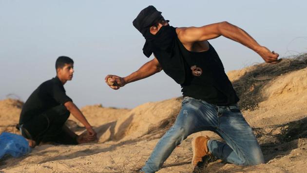 A Palestinian protester hurls stones at Israeli troops during clashes near the border between Israel and Central Gaza Strip. (REUTERS/Ibraheem Abu Mustafa )