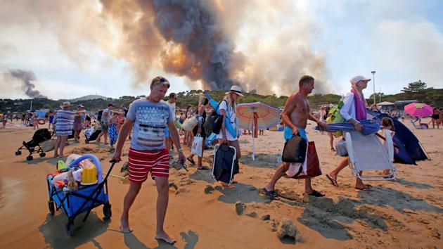 Tourists evacuate the beach as smoke fills the sky above a burning hillside in Bormes-les-Mimosas in the Var department, France. (REUTERS/Jean-Paul Pelissie)
