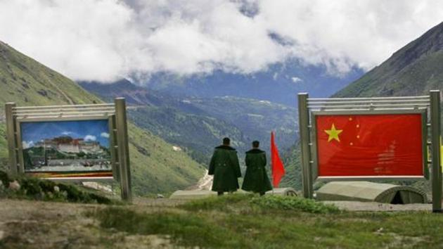 Chinese army officers oversee preparations as they stand between pictures of the Patola Palace, and the Chinese flag, on the Chinese side of the international border at Nathula Pass, in Sikkim on July 5, 2006.(AP File Photo)