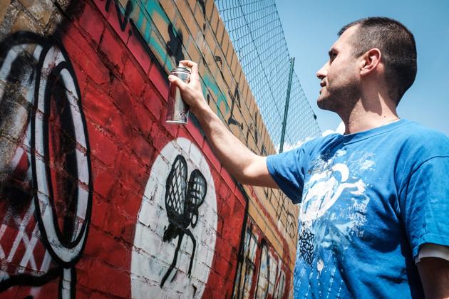 Picture taken on May 11, 2016 shows street artist Ibo Omari overpainting a swastika in Berlin.(AFP)