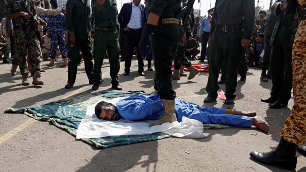 In line with Yemeni legal practice, al-Maghrabi was brought into the square in an inmate’s jumpsuit and placed face down, handcuffed with police officers wielding machine guns standing over him. (Khaled Abdullah / REUTERS)