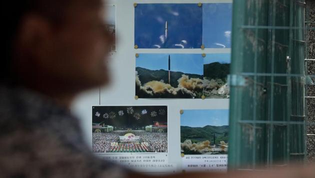 A man drives his car past a display board showing photos of ballistic missile launches in North Korea outside the North Korean Embassy in Beijing on August 3.(AP Photo)