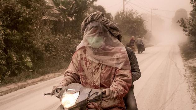 Motorists cover their faces as thick ashes blanket Tiga Pancur village in Karo, North Sumatra. (IVAN DAMANIK/ AFP)