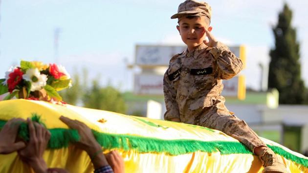 The son of Hezbollah commander Fadi Shahouri, gestures as he sits on his father's coffin during his funeral near Nabatieh in southern Lebanon. (Ali Hashisho / REUTERS)