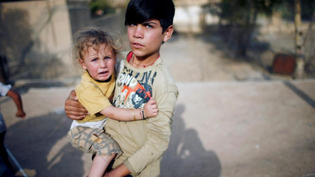 A Yazidi boy holds his sister in a playground in Sinjar region, Iraq. (Suhaib Salem / REUTERS)