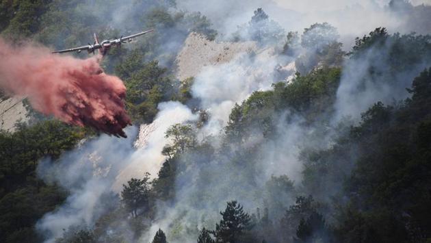 A plane drops flame retardant to put out a fire in Rigaud, north of Nice, southeastern France. France has been battling for several weeks huge fires near beaches popular with tourists on the Cote d'Azur, forcing the evacuation of people. (Yann COATSALIOU / AFP)